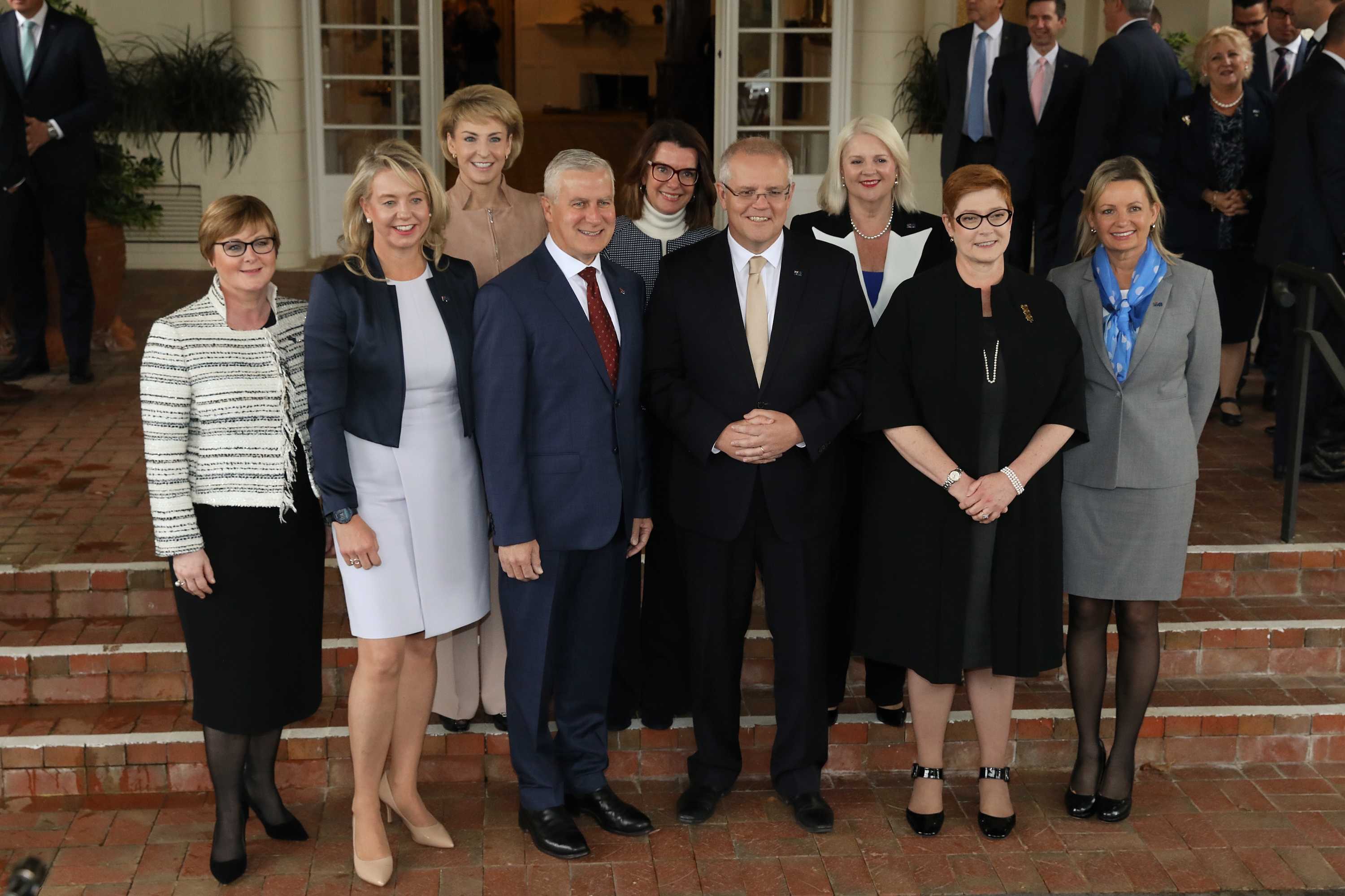 Mr Morrison and Mr McCormack are surrounded by the female members of Cabinet, as they stand on the steps of Government House.